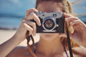 Frau mit alter Kamera am Strand